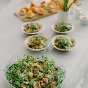A healthy vegetable salad topped with microgreens on a table setting.