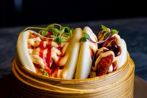 Gourmet bao buns with vibrant toppings in a bamboo steamer. Perfect fusion cuisine shot.