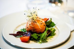 A gourmet salad featuring smoked salmon, fresh greens, and cherry tomatoes elegantly presented.