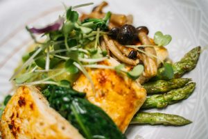 Delicious tofu meal served with crispy asparagus and sautéed mushrooms.