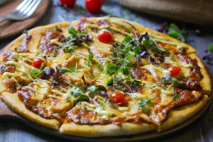 Close-up of a gourmet pizza topped with fresh greens and cherry tomatoes, perfect for food photography.