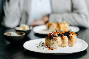 Close-up of sushi roll with garnish on a ceramic plate, capturing Japanese cuisine.
